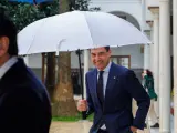 El presidente andaluz, Juanma Moreno, se protege de la lluvia a su llegada este jueves a la sesi&oacute;n de control en el Parlamento.