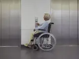 Una mujer en silla de ruedas se dispone a coger un ascensor.