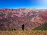 Persona posando delante de El Hornocal, se trata de montañas de colores de la Quebrada de Humahuaca, una zona al noroeste de Argentina delarada Patrimonio de la humanidad.