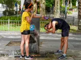 Una turista le refresca la cabeza a un joven mientras para atenuar el calor