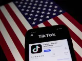 Un teléfono con la aplicación TikTok sobre una bandera de EEUU.