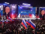 El presidente y candidato presidencial ruso, Vladimir Putin, aparece en pantallas gigantes mientras asiste a un concierto para conmemorar el décimo aniversario de la reunificación de Crimea con Rusia en la Plaza Roja de Moscú.