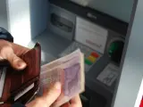Un persona sacando dinero de un cajero automático.