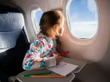 Una niña en un avión con lápices de colores.
