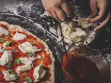 Persona preparando una pizza.