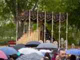 La Virgen del Subterráneo, de la Hermandad de la Sagrada Cena, a su paso por la Carrera Oficial, juntos a numerosas personas que observan su paso con los paraguas abiertos.