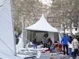Varias personas recogen piezas del suelo tras volarse las carpas ubicadas en la Feria de la Artesanía de Valladolid.