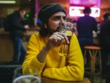 Un joven bebiendo cerveza en un bar.
