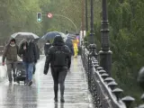 Peatones caminan bajo la lluvia en Sevilla, este domingo.