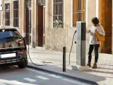Una mujer recarga la batería de su coche eléctrico en un punto de carga.