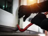 Una persona forzando una ventana para entrar robar en un domicilio.