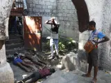 Varias personas observan los cuerpos de tres personas muertas a tiros tras un tiroteo nocturno en el barrio de Pétion Ville de Puerto Príncipe.