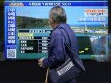 Una persona de pie a lo largo de una acera para ver un televisor que muestra una noticia de última hora sobre el tsunami en la región de Okinawa miércoles, 3 de abril 2024, en Tokio.