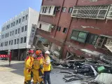 En esta fotografía publicada por la Agencia Nacional de Bomberos, miembros de un equipo de búsqueda y rescate se preparan cerca de un edificio inclinado después del terremoto en Hualien (Taiwán).
