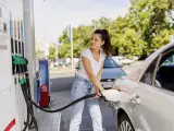 Una mujer repostando su vehículo en una gasolinera.