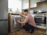 Un hombre poniendo la lavadora.