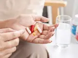 Una mujer con cápsulas de medicamentos en la mano.