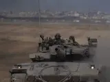 Soldados israelíes se mueven sobre un tanque cerca de la frontera entre Israel y Gaza.