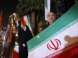 Varias personas sostienen banderas iraníes y palestinas durante una manifestación contra Israel después de que Irán lanzara ataques con drones.
