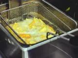 Patatas friéndose en una freidora con aceite.