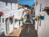 Calle empedrada con casas blancas y macetas de flores en Mijas, Málaga.