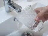 Una persona llena un vaso de agua de un grifo.