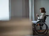Una mujer con discapacidad mirando por la ventana