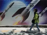 Una mujer camina junto a una pancarta que muestra misiles en Teherán este viernes 19 de abril.