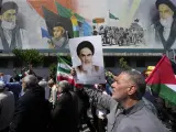 Manifestantes iraníes pasan junto a un mural que muestra al difunto fundador revolucionario Ayatolá Jomeini (derecha), el Líder Supremo Ayatolá Ali Jamenei (izquierda) y la fuerza paramilitar Basij.