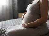 Mujer embarazada sentada en la cama.
