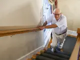 Un señor mayor sube las escaleras de su casa.