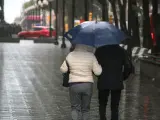 Dos personas pasean con paraguas por la Rambla Nova de Tarragona.