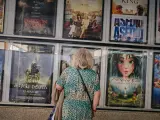 Una señora mayor frente a la cartelera de un cine.