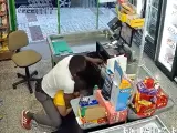 El asaltante realizándole la técnica a la cajera de un supermercado.