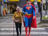 Superman ayuda a una señora a cruzar la calle.