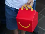 Un niño sostiene la caja de un menú Happy Meal de McDonald's.