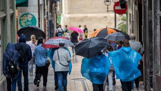 Turistas y transeuntes caminan bajo la lluvia este lunes 29 de mayo en Logroño