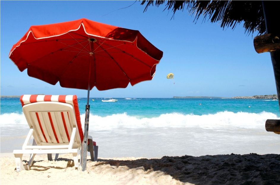 Image of an umbrella and a deckchair on a beach.