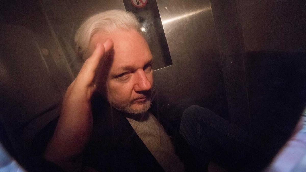 Julian Assange ผู้ก่อตั้ง WikiLeaks โบกมือให้ช่างภาพขณะออกจาก Southwark Court ในรถตำรวจในลอนดอน