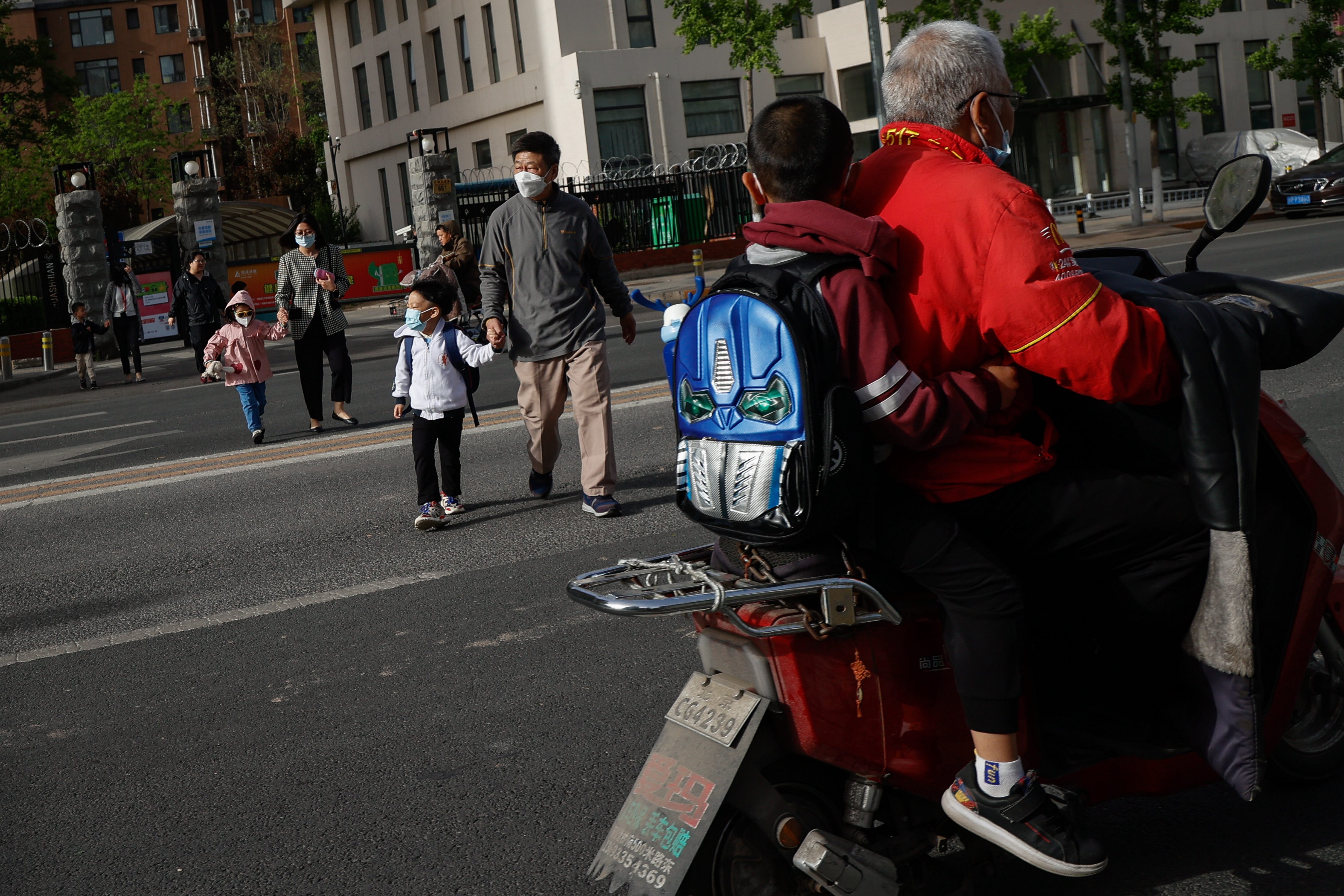 Los padres caminan junto a sus hijos por las desiertas calles de Pekín.