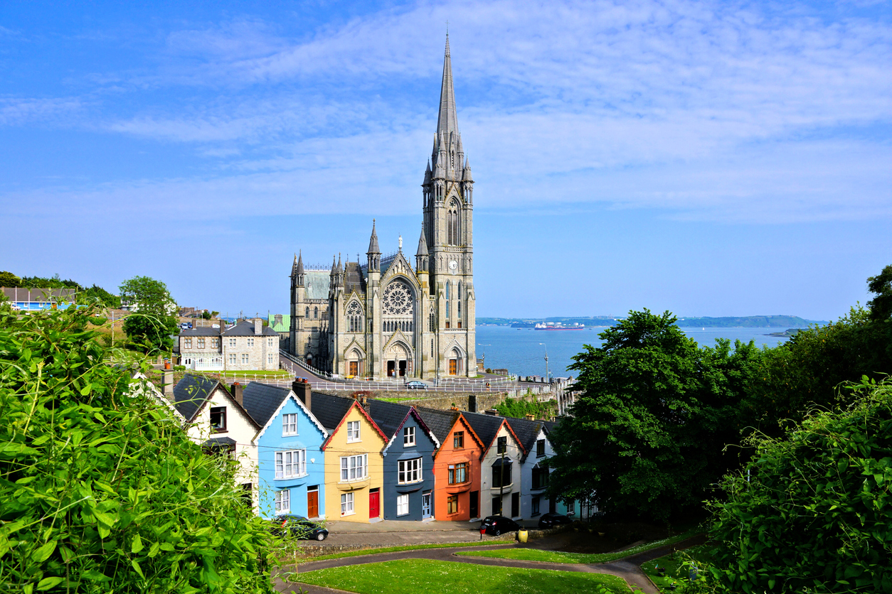 Coloridas casas adosadas con una imponente catedral al fondo en la ciudad portuaria de Cobh, Condado de Cork, Irlanda
