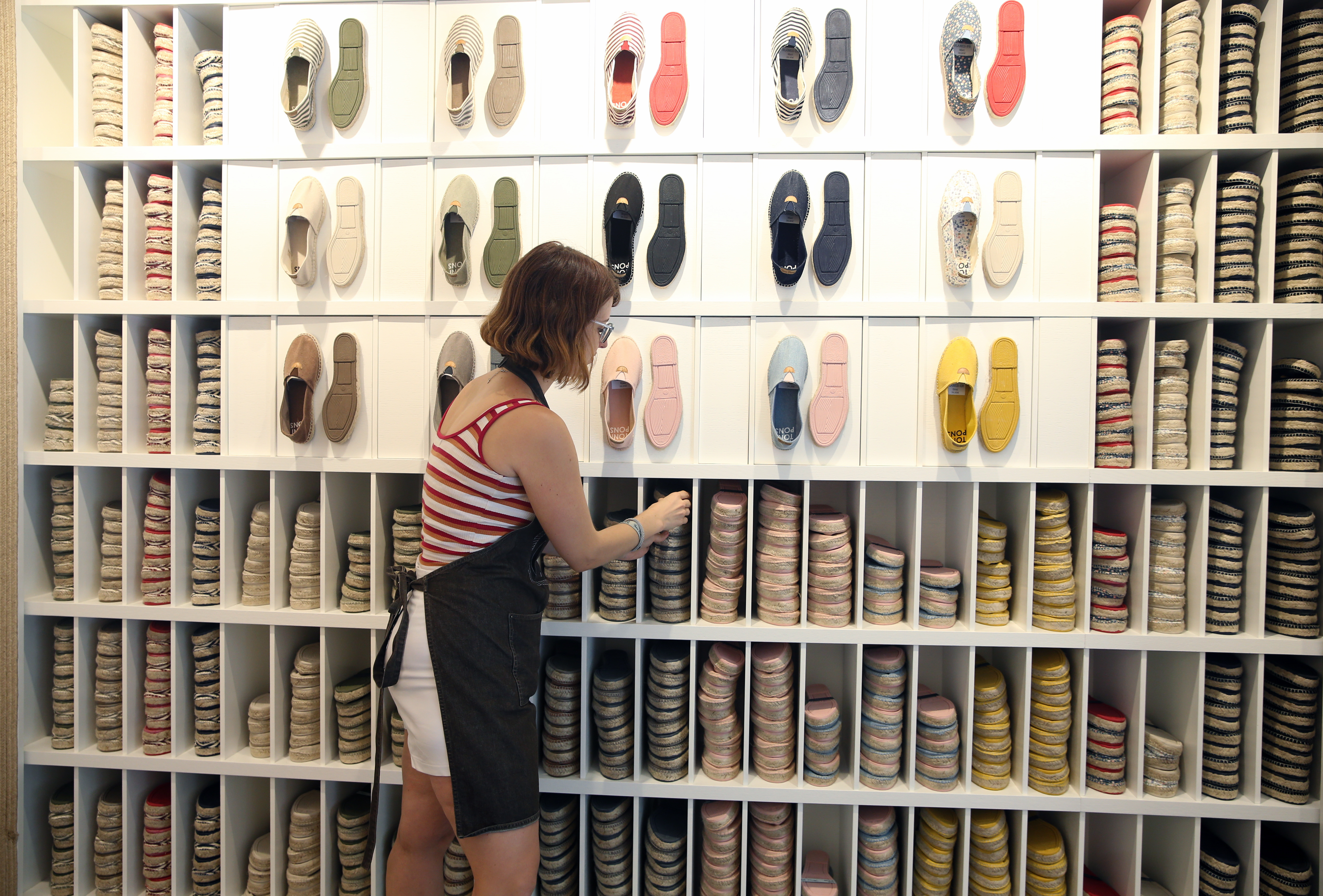 An employee at a shoe store places products in her store.