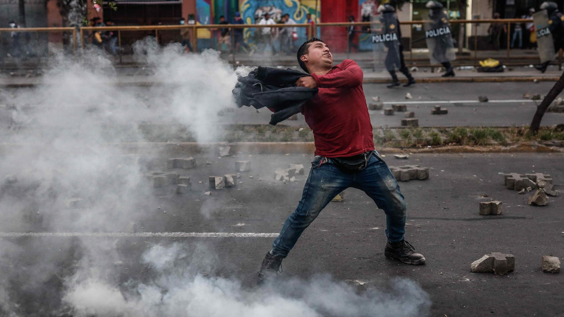Un manifestante en favor de Pedro Castillo se enfrenta a la Policía en las afueras de la Prefectura de Lima, donde permanece detenido el expresidente peruano.