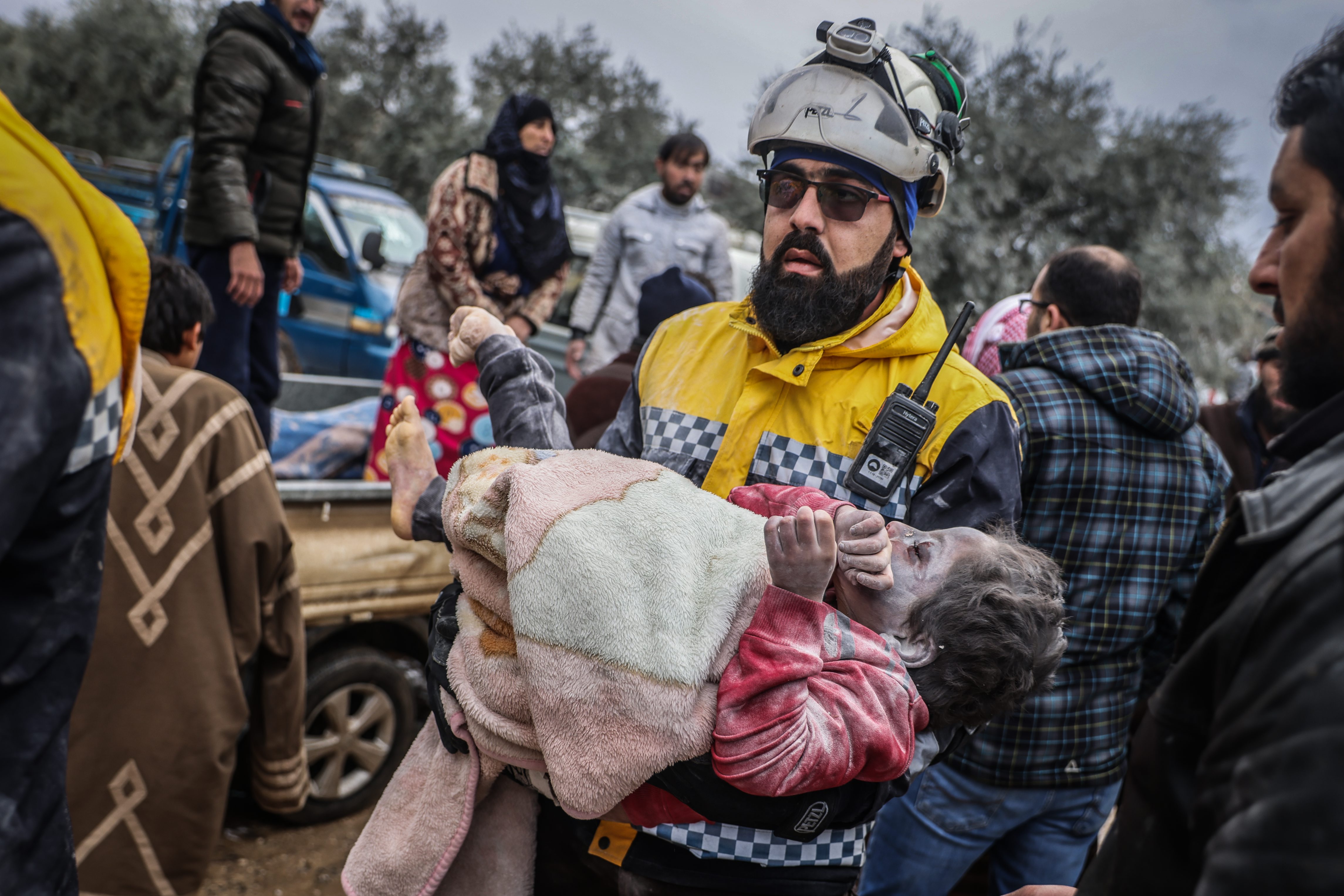 Un miembro de los Cascos Blancos de Siria traslada en brazos a un niña que ha sido recuperada con vida bajo los escombros de un edificio derrumbado por el terremoto en la ciudad de Harem.