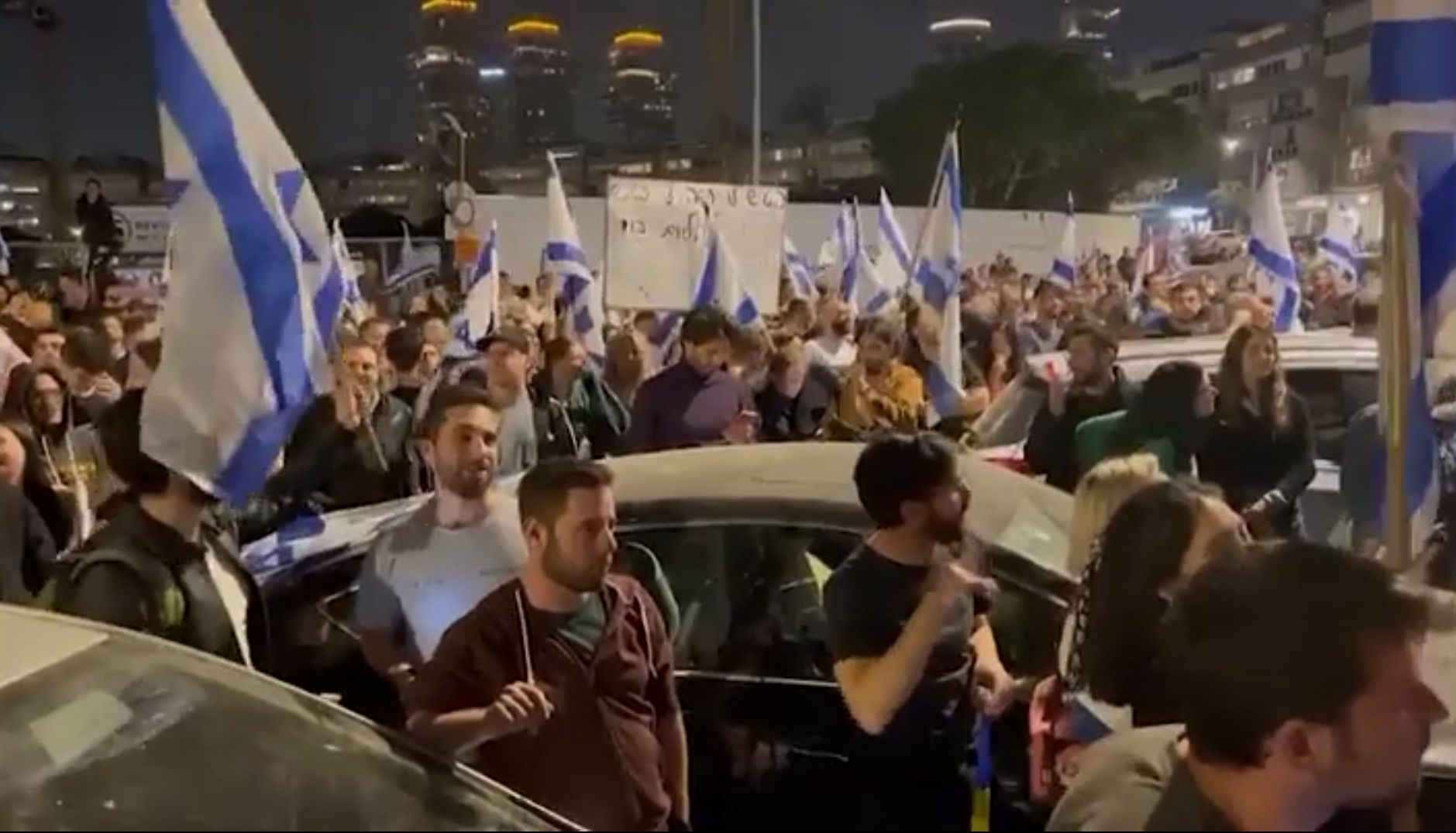 Con banderas y abucheos, cientos de manifestantes se reúnen frente a una peluquería en Tel Aviv.
