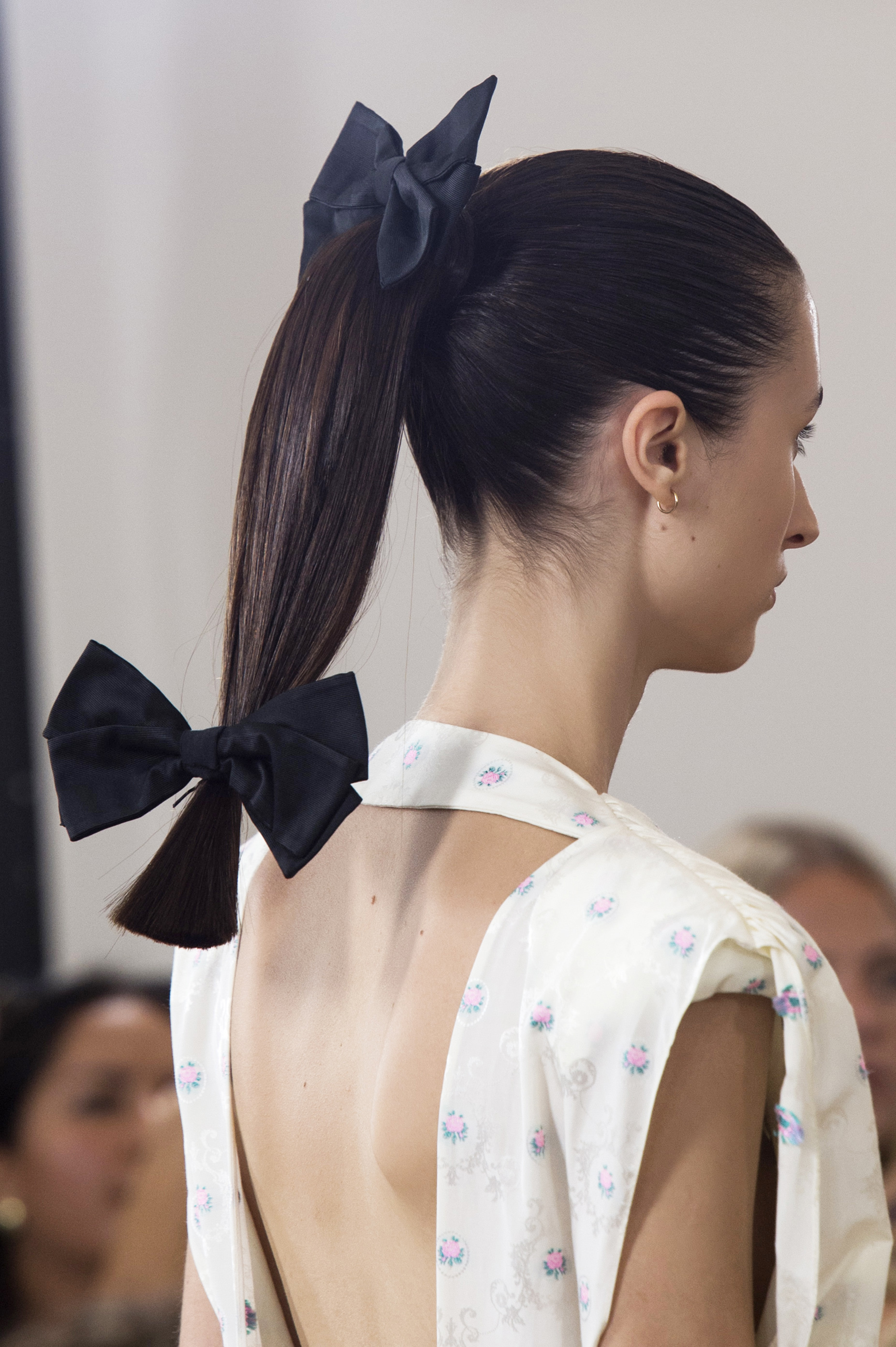 A model wears a high ponytail decorated with bows.